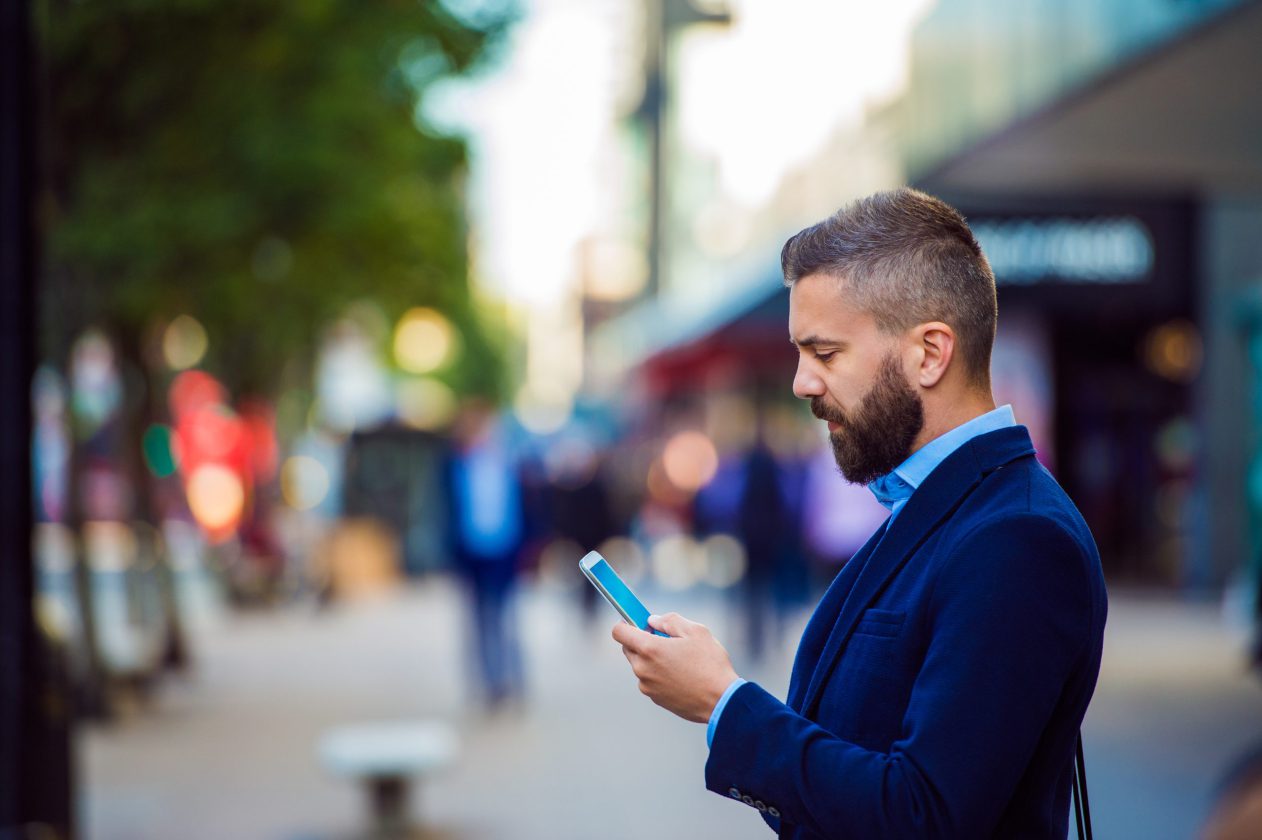 REALTOR holding smartphone, texting outside in the stree